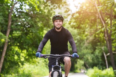 Portrait of excited young biker riding bicycle in greens