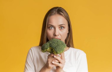 Young Woman Eating Broccoli, Biting Healthy Vegetable With Wide-Opened Eyes