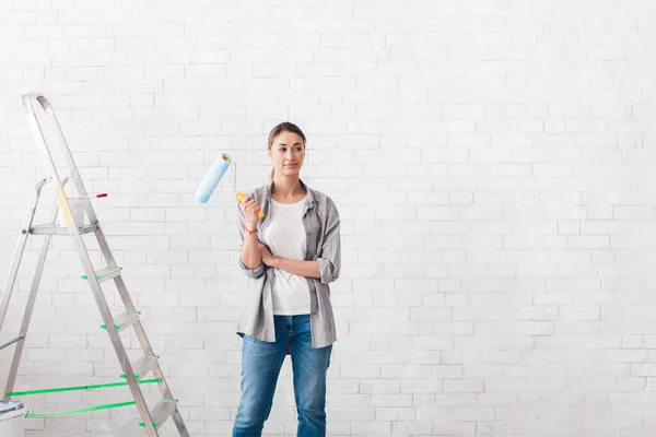 Young woman holding a roller for painting walls in new house — Φωτογραφία Αρχείου