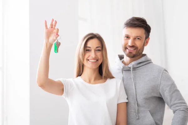 Happy married couple holding keys from new dwelling — Stock Photo, Image