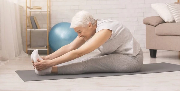 Mujer mayor activa haciendo ejercicios de estiramiento en casa — Foto de Stock