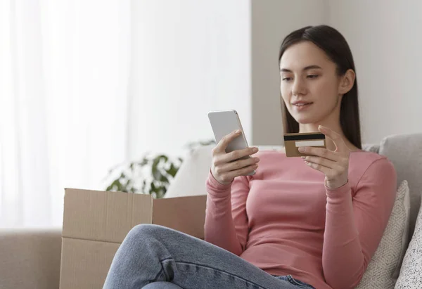 Woman holding credit card and inputting card information with cellphone — Stock fotografie