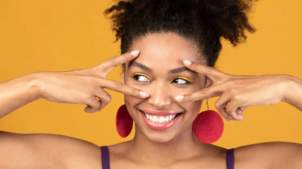 Menina afro feliz mostrando v sinal no estúdio laranja — Fotografia de Stock