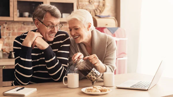 Счастливая пожилая пара пьет кофе, расслабляясь вместе на кухне — стоковое фото