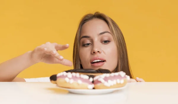 Ragazza affamata che prende dolci dal piatto, fantasia di cibo spazzatura malsano — Foto Stock