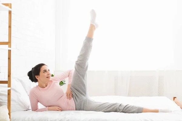 Mulher milenar esticando as pernas na cama — Fotografia de Stock