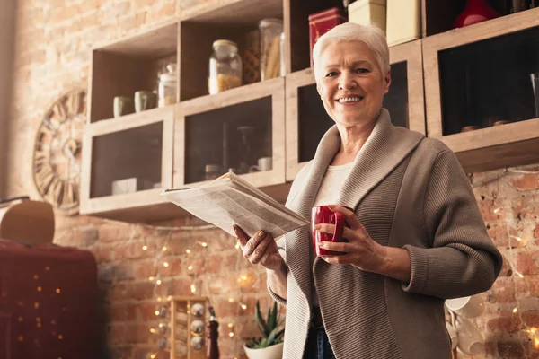 Aged Woman Reading Morning Newspaper And Drinking Coffee In Kitchen — Stockfoto