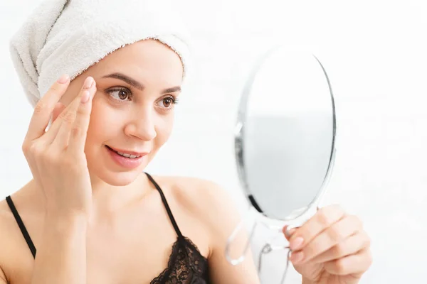 Milenial mujer masajeando su cara, mirando al espejo — Foto de Stock