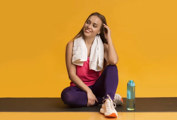 Mulher jovem relaxante após o treino com toalha no pescoço e na água — Fotografia de Stock