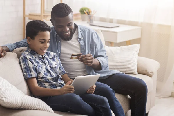 Feliz afro padre e hijo con tarjeta de crédito y tableta digital — Foto de Stock
