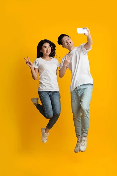Beautiful asian couple taking selfie while jumping up — Zdjęcie stockowe