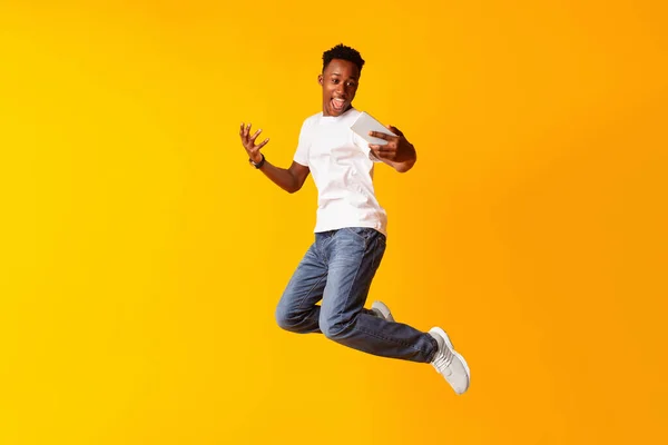 African guy jumping for connecting the internet on his cell phone — Zdjęcie stockowe