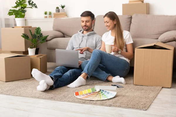 Young couple sitting in new apartment with unpacked boxes — Stock Fotó