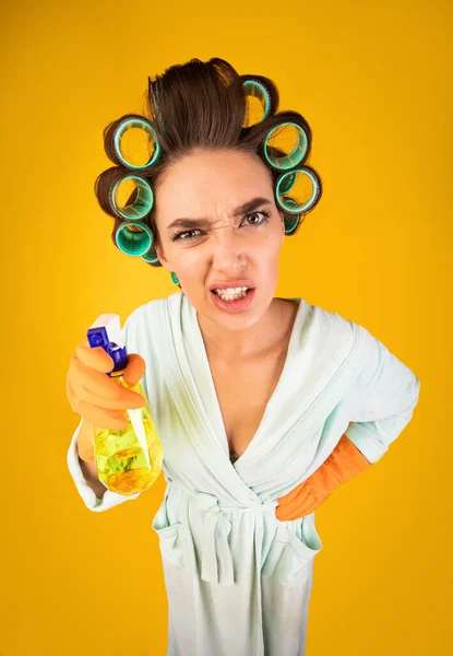 Angry Housewife Holding Detergent Bottle Standing Over Yellow Background, High-Angle
