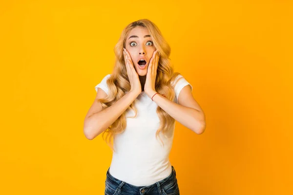 Shocked girl with open mouth touching her cheeks with hands — Stock fotografie