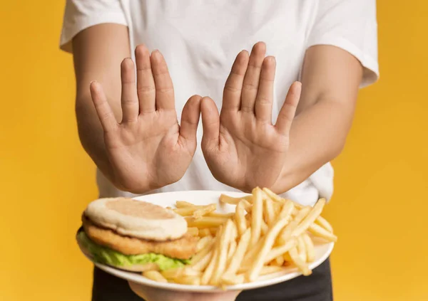 Donna irriconoscibile che rifiuta di consumare piatto con cibo spazzatura, mostrando stop gesti — Foto Stock