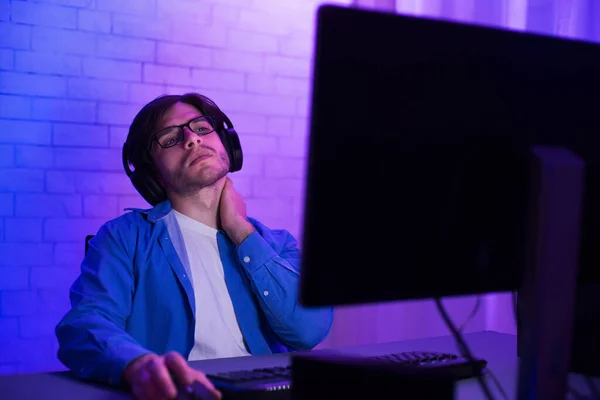 Втомлений програміст працює на комп'ютері торкаючись шиї вдома — стокове фото