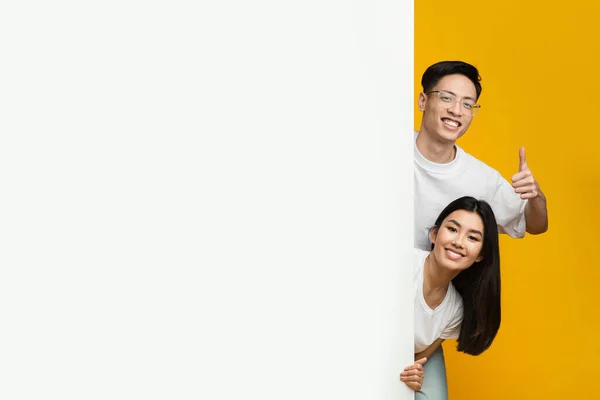 Asian happy couple standing next to empty advertising board — Zdjęcie stockowe