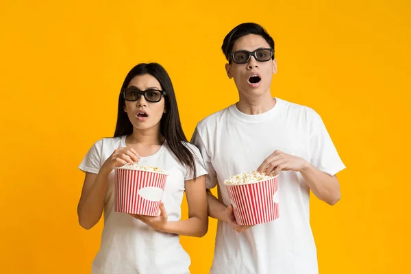Stunned asian couple in 3d glasses watching movie with popcorn — Stockfoto