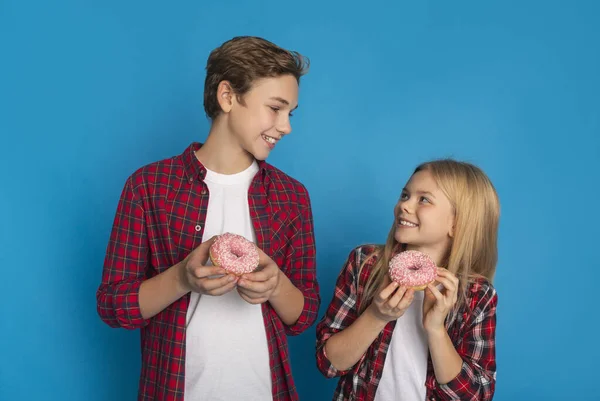 Братья и сёстры. Happy Little Brother and Sister Holding Sweet Tasty Donuts — стоковое фото