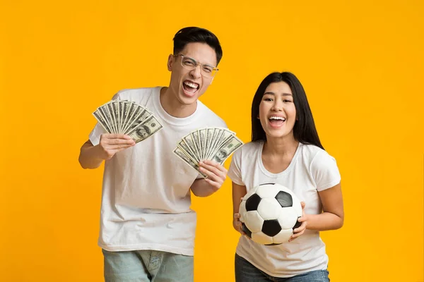 Feliz asiático pareja holding bola y manojo de dinero — Foto de Stock