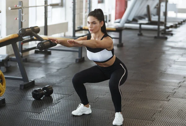 Young woman doing squats in sports club — Stok fotoğraf