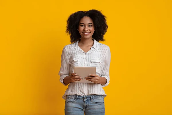 Mujer afro milenaria con tableta digital en las manos sonriendo a la cámara — Foto de Stock