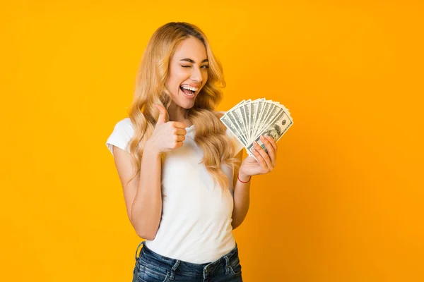 Cashback. Mujer excitada sosteniendo billetes de dinero y mostrando el pulgar hacia arriba — Foto de Stock