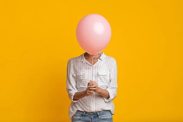 Irreconhecível preto menina escondido rosto atrás rosa balão — Fotografia de Stock