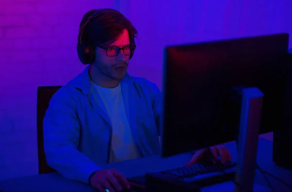 Joueur à l'ordinateur jouant à des jeux de tir assis dans la chambre noire — Photo