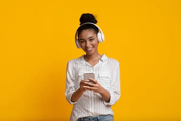 Happy Afro Girl avec smartphone et écouteurs sans fil écoutant de la musique préférée — Photo
