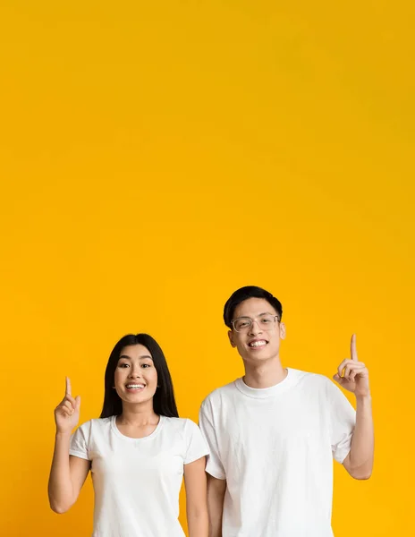 Excited asian man and woman pointing upwards — 图库照片