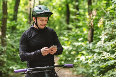 Happy cyclist holding smartphone, checking on messages