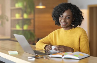 Smiling black woman having coffee break while looking for job