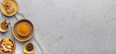 Healthy turmeric spice powder, honey and other spices on gray