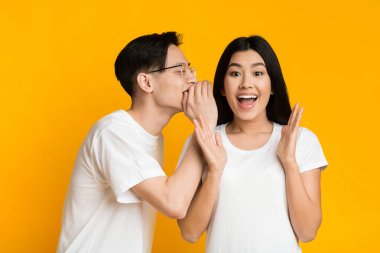 Asian man sharing secret with his emotional girlfriend