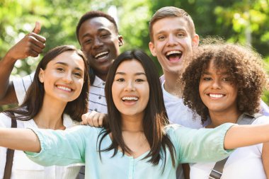 Group of multi-ethnic teen friends taking selfie picture outdoors