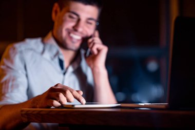 Unrecognizable Entrepreneur Using Tablet Talking On Cellphone Working In Office