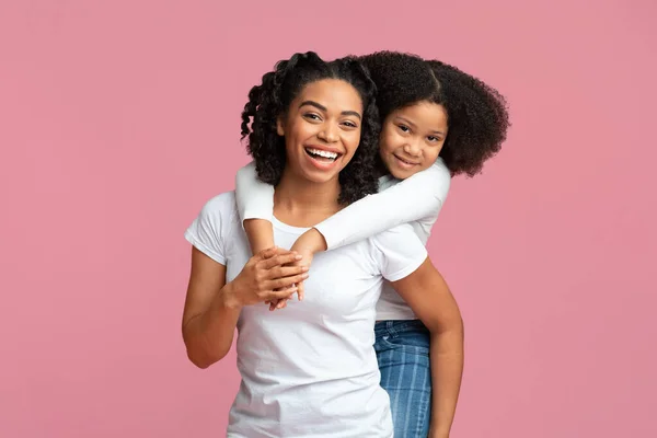 Little Black Girl Embracing Her Mother From Behind On Pink Background — Φωτογραφία Αρχείου