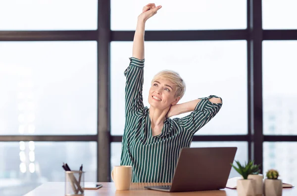Empresária bem sucedida esticando as mãos sentadas no escritório moderno — Fotografia de Stock