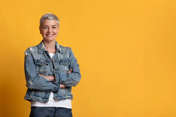 Portrait of beautiful mature woman smiling at camera over yellow background — Stock fotografie
