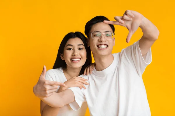 Young asian couple showing frame sign with fingers — Zdjęcie stockowe