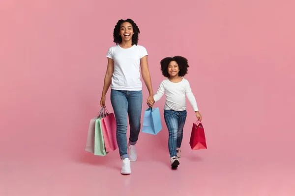 Black Mother And Daughter Walking With Shopping Bags On Pink Background — Stockfoto