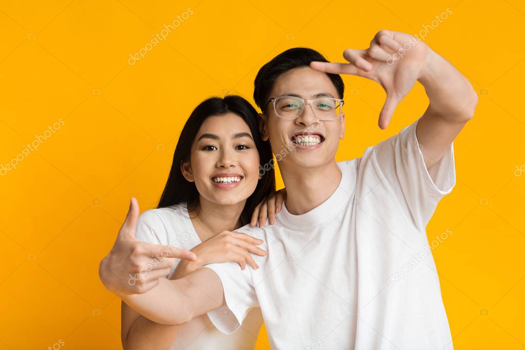 Young asian couple showing frame sign with fingers