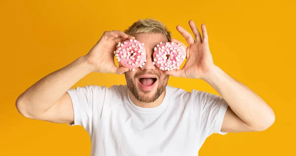 Guy have fun, holds donuts near eyes — Stock Photo, Image