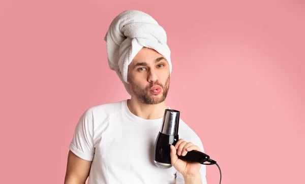 Kerel blaast in föhn met handdoek op zijn hoofd — Stockfoto