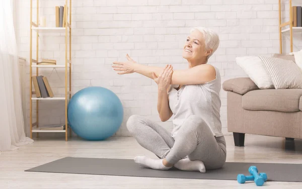 Positivo deportivo senior mujer calentando en casa — Foto de Stock