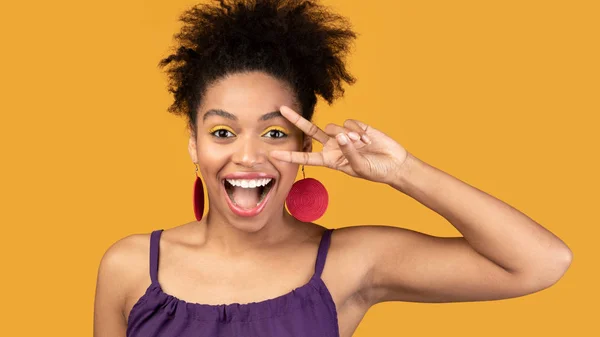 Opgewonden afro meisje tonen v teken kijken naar camera — Stockfoto