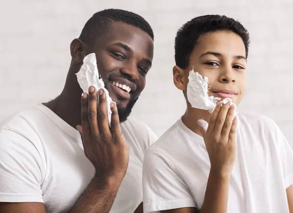 Feliz afro-americano padre e hijo poniendo espuma de afeitar en caras — Foto de Stock