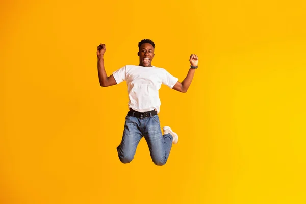 Knappe Afrikaanse man springt tegen gele achtergrond — Stockfoto
